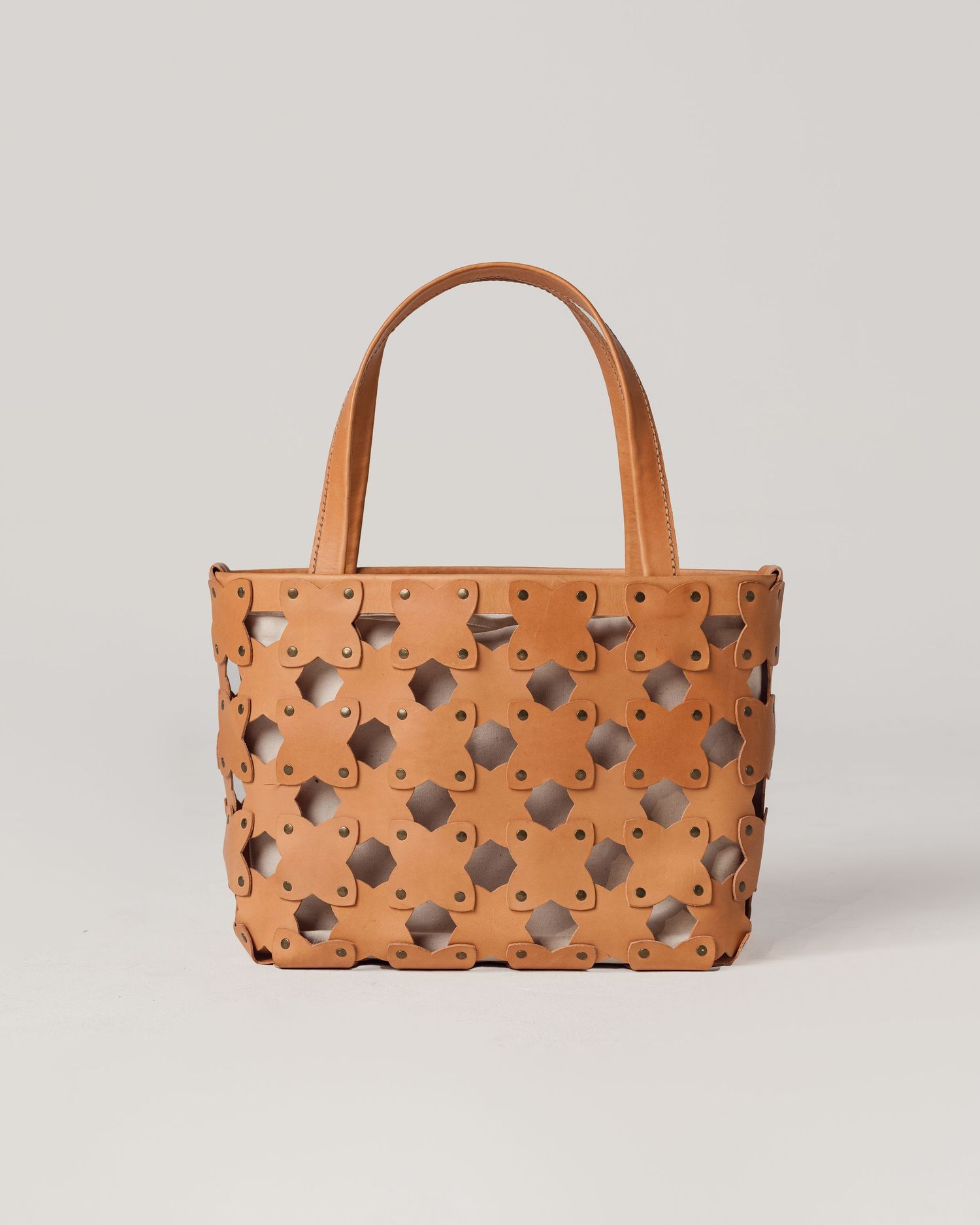 Handcrafted tan leather handbag with geometric cutout pattern shown from multiple angles on white background.
