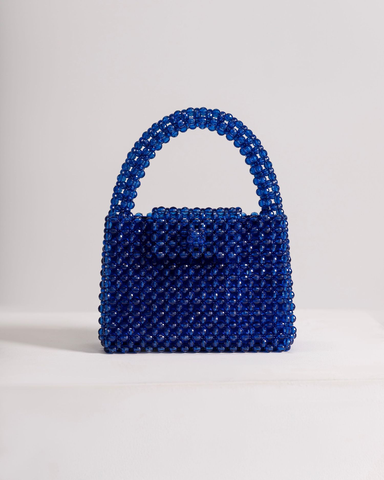 Royal blue beaded mini handbag with structured silhouette and looped top handle, crafted from shiny faceted beads.