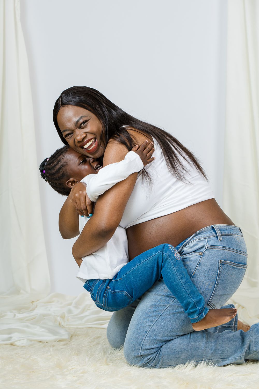 Loving embrace captured on white backdrop with flowing curtains.