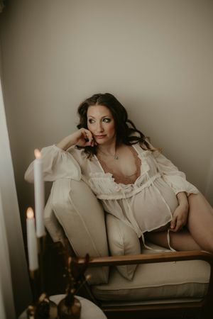 A series of moody boudoir photos featuring someone in a vintage white blouse reclining on antique furniture with candlelight.
