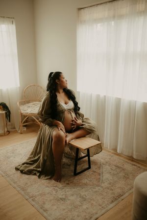 Artistic indoor portrait series featuring soft lighting and sheer curtains in neutral toned room.
