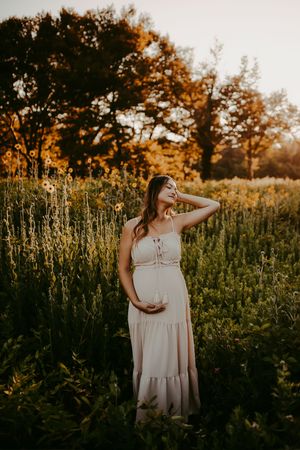 Golden hour portrait session in a field of tall wildflowers with soft lighting.