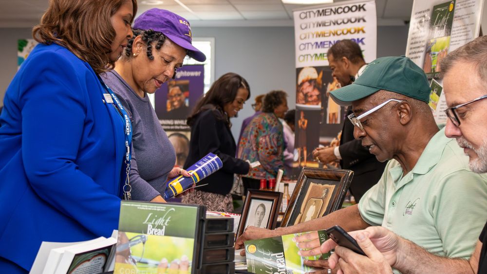 People browsing books at an indoor book fair event with vendors displaying titles on tables.