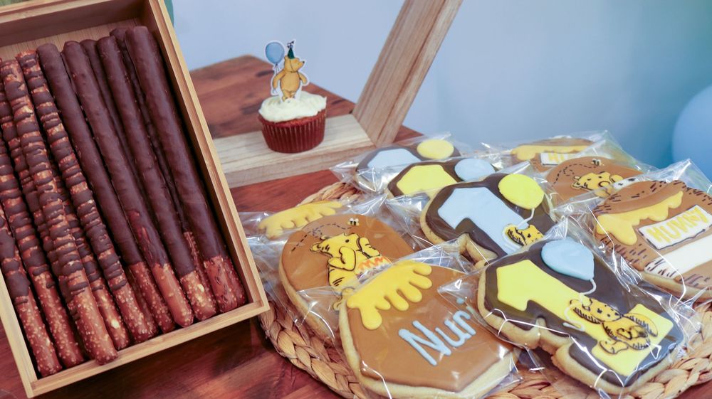 Decorative graduation cookies and cupcakes with gold and brown themed designs on a dessert table.
