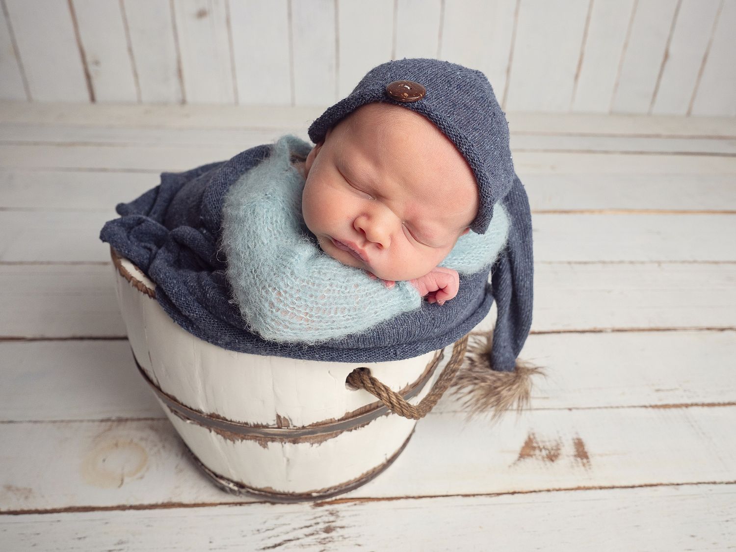 newborn baby in bucket with blue hat