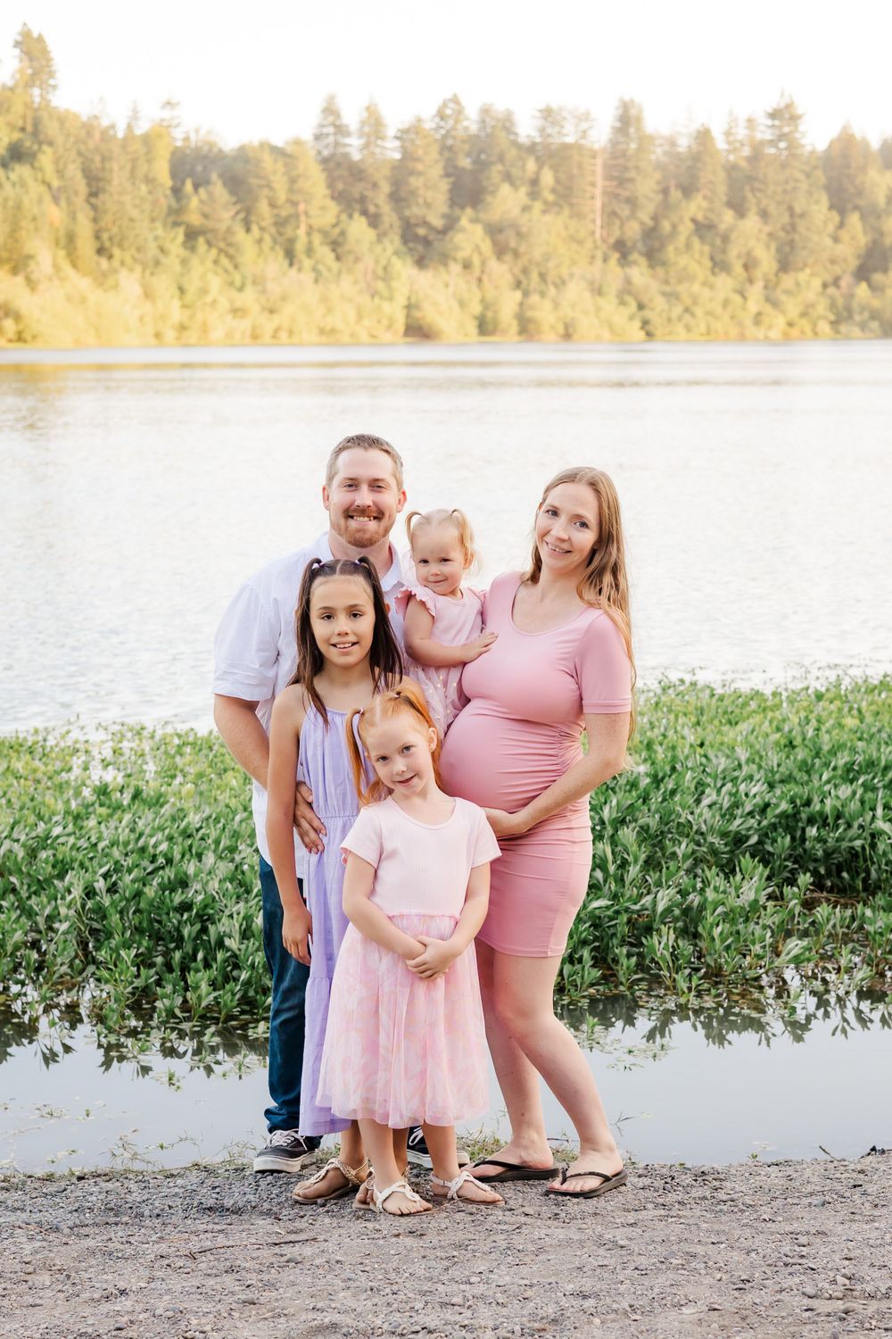 family of 2 parents and 3 little girls standing next to a river at sunset. family photographer Sonoma county