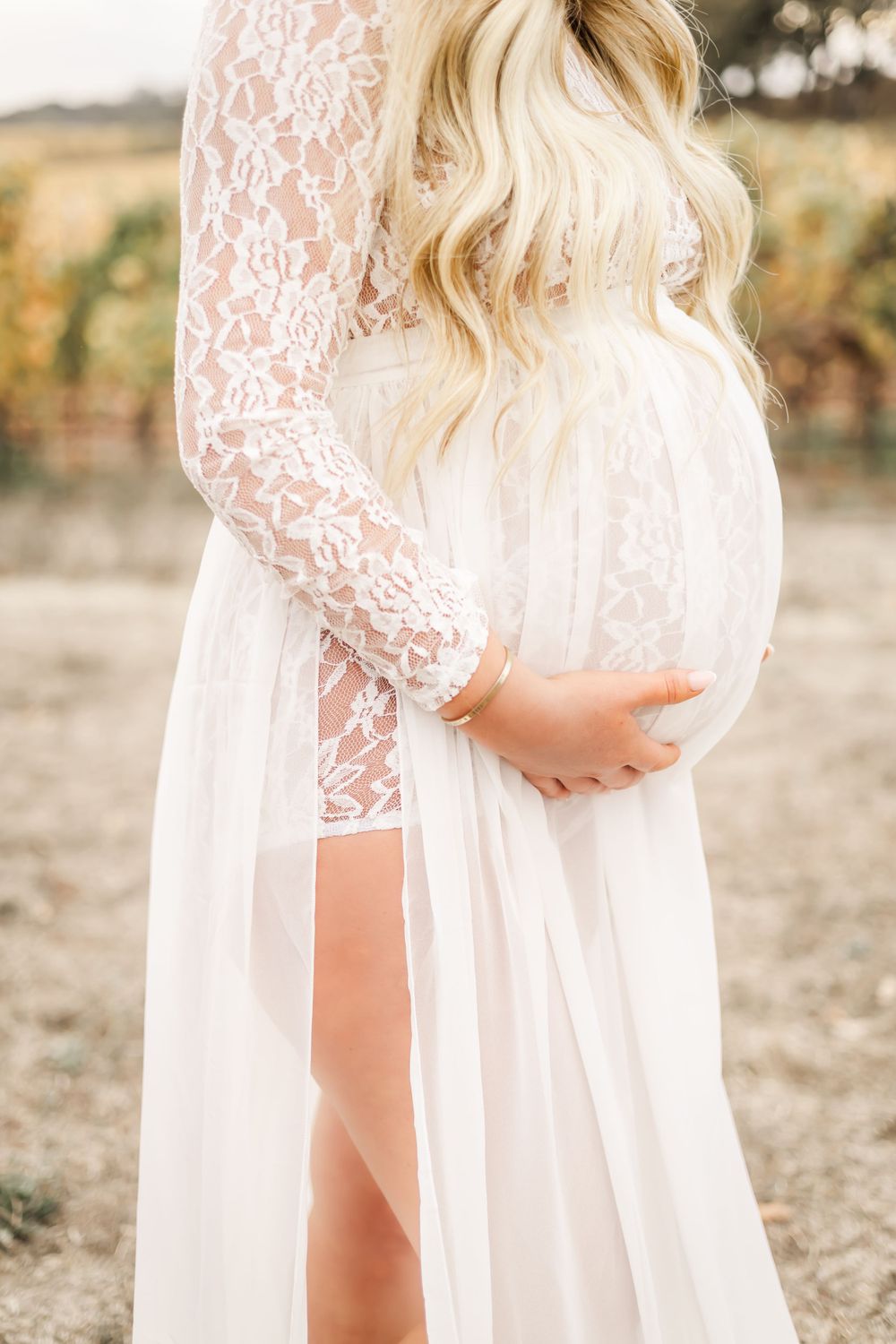 luxury maternity photographer in a vineyard in Sonoma County. pregnant woman in long, flowy white lace dress at sunset.