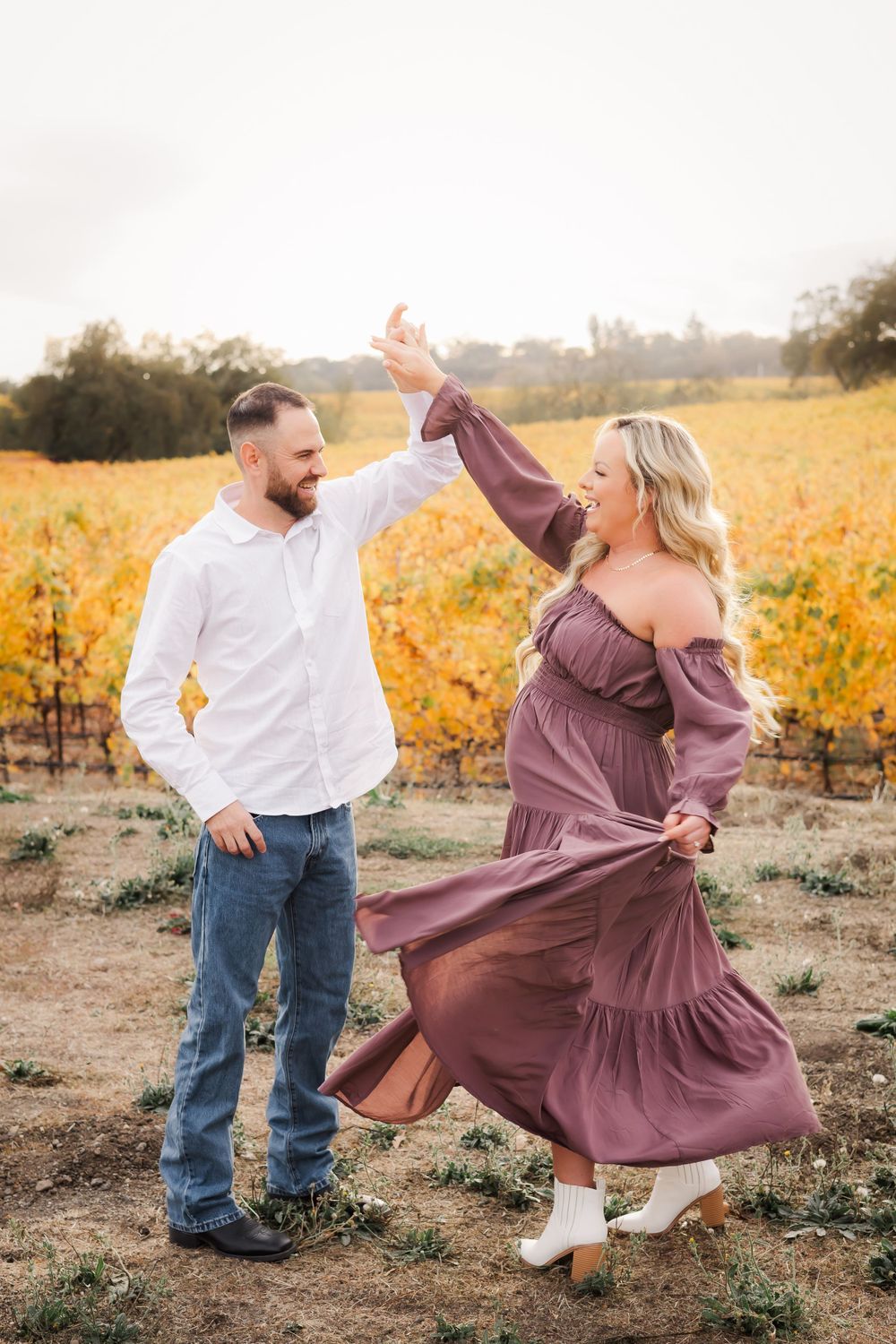 pregnant woman dancing with husband in vineyard at sunset. maternity session