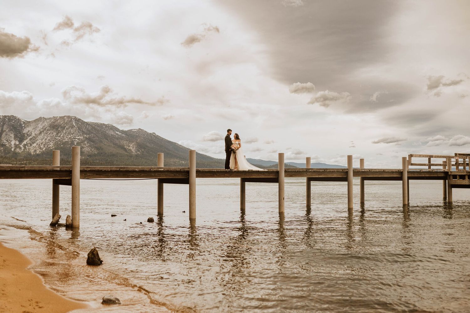 Bride and groom share a joyful embrace outdoors at a rustic woodland wedding ceremony.