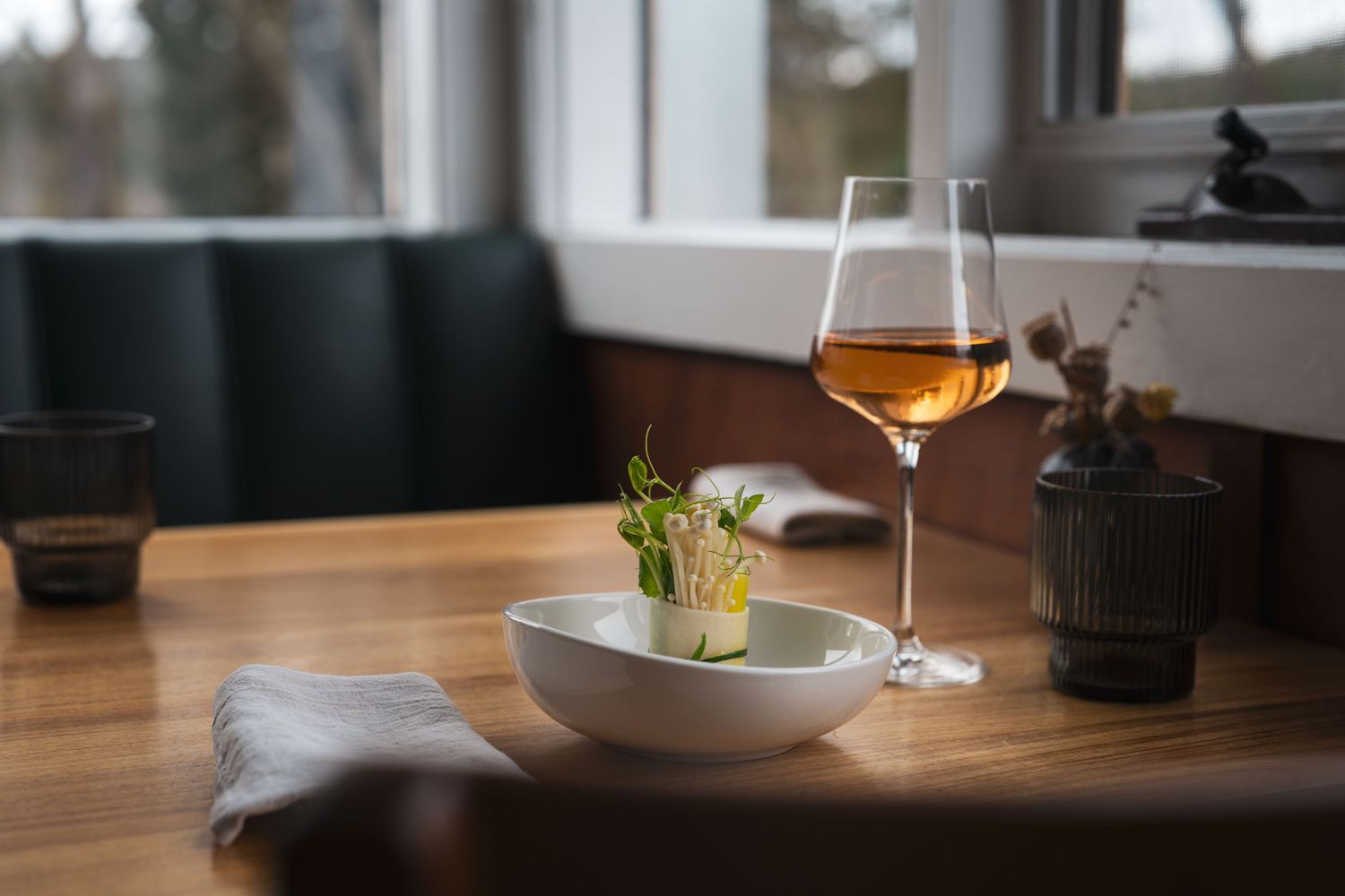 Elegant restaurant table setting with a bowl of food and a glass of rose wine by a window.

The Surly Goat
