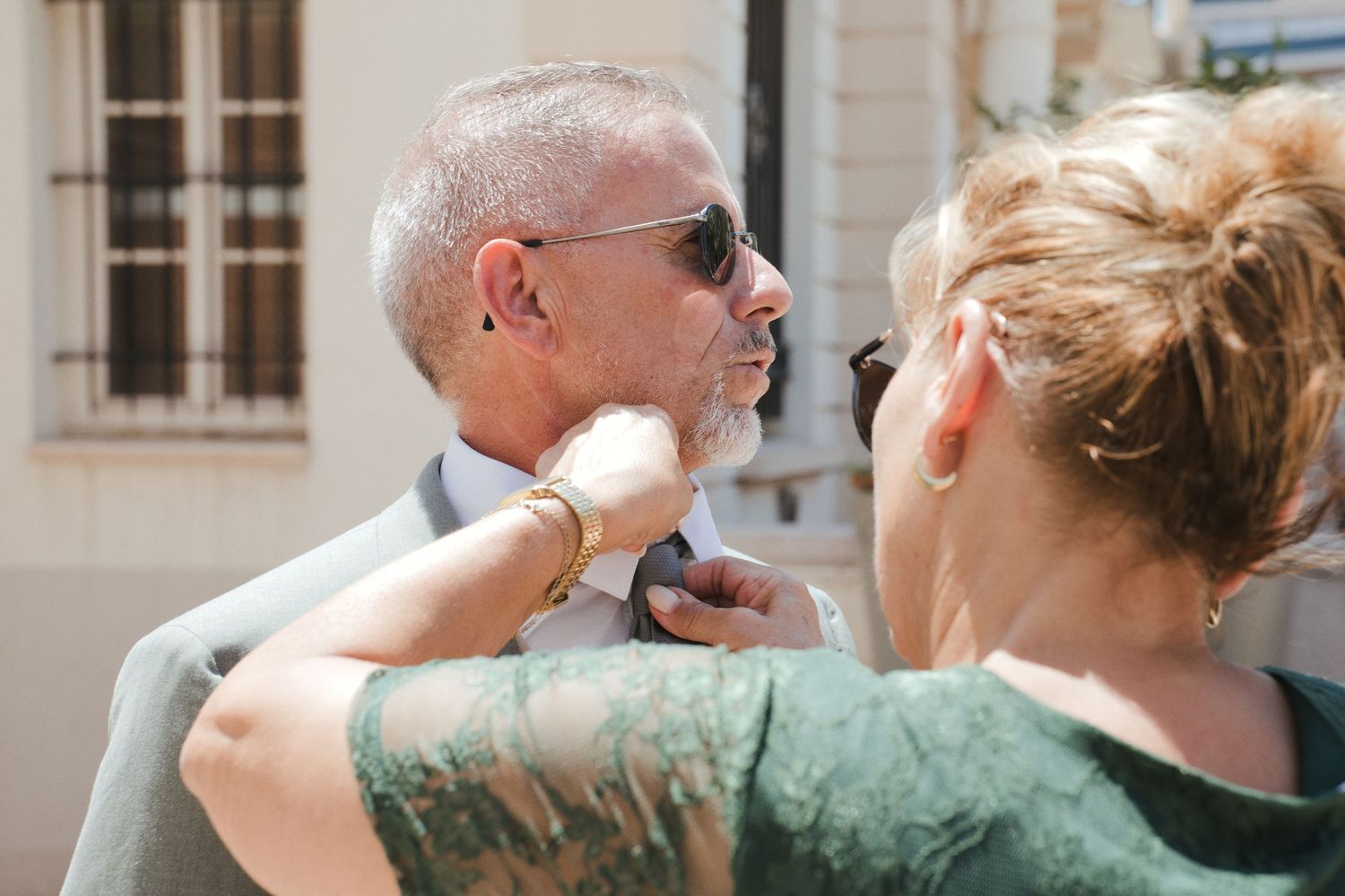 Une invitée ajuste le col de chemise d’un homme avant la cérémonie.