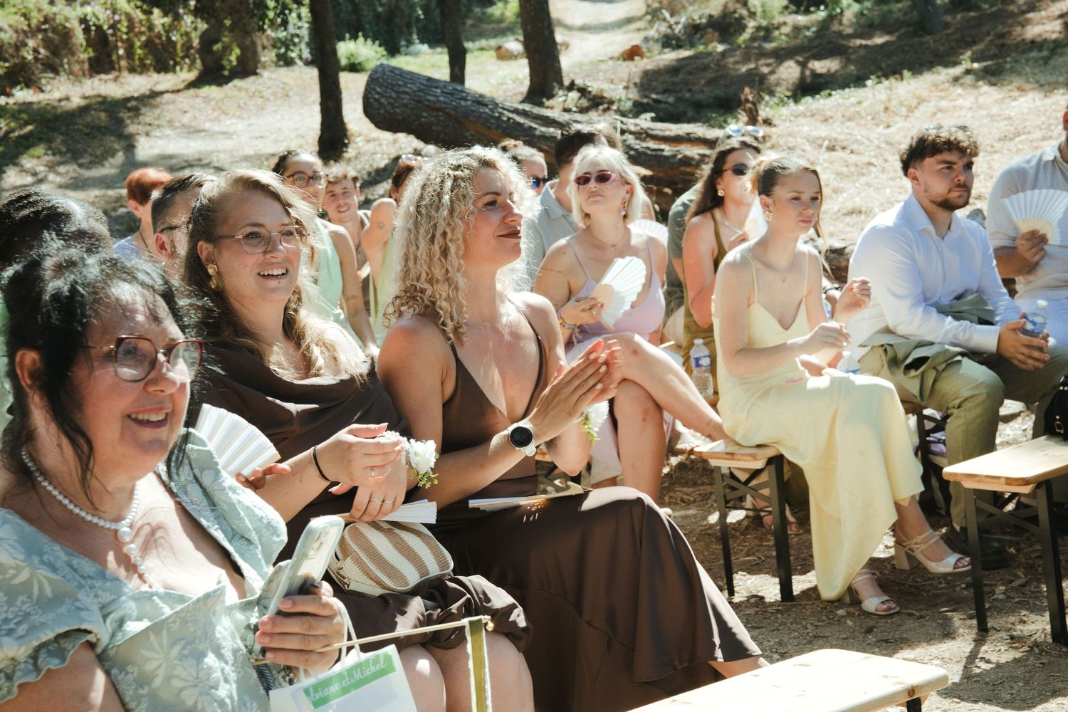 Les invités assis au soleil pendant une cérémonie de mariage en extérieur.