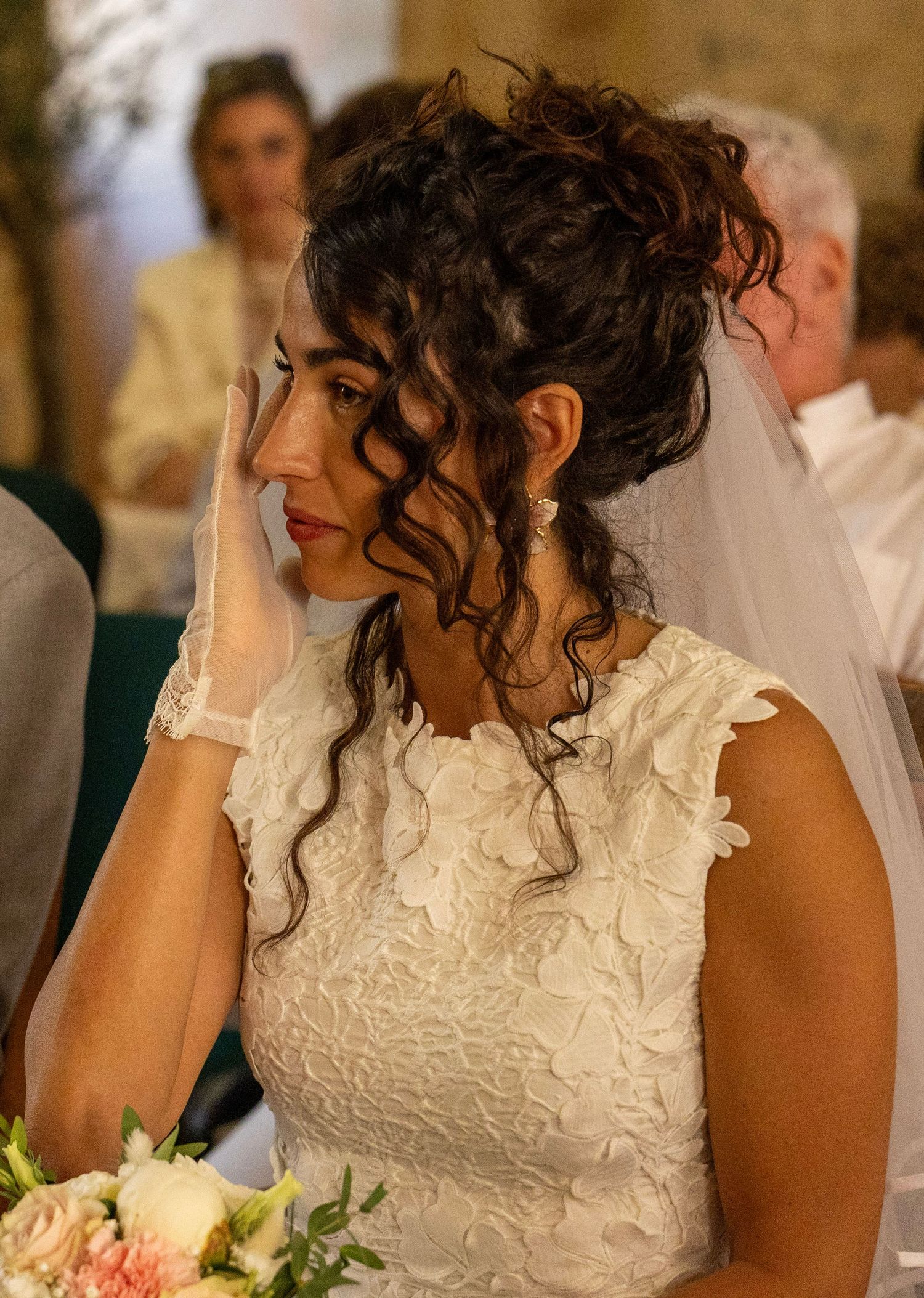 La mariée essuie une larme pendant la cérémonie de mariage.
