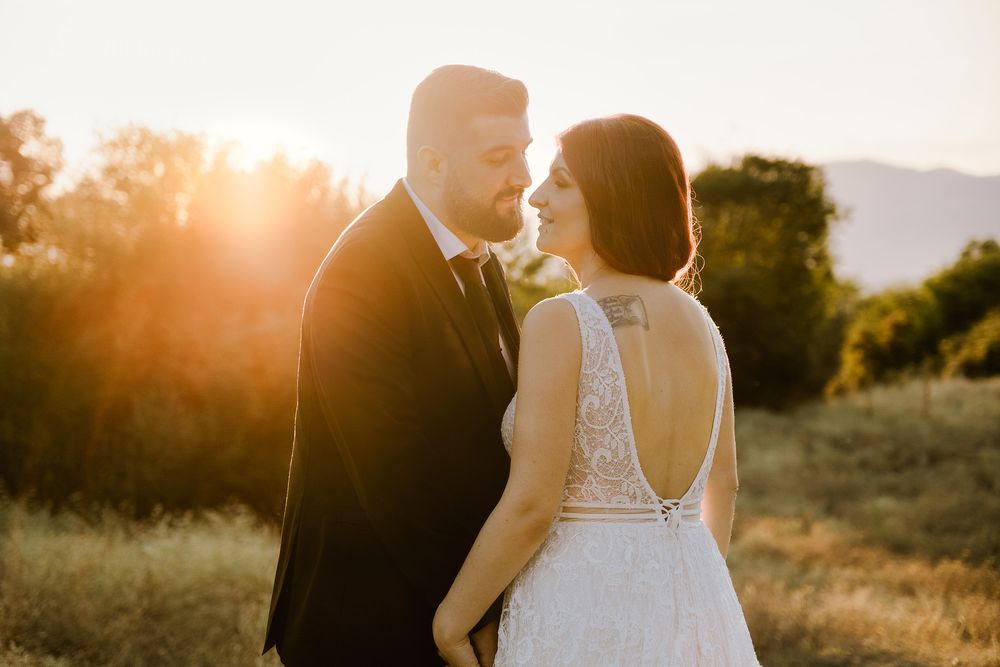 Newlyweds holding hands in a field during a golden hour sunset in Greece.
