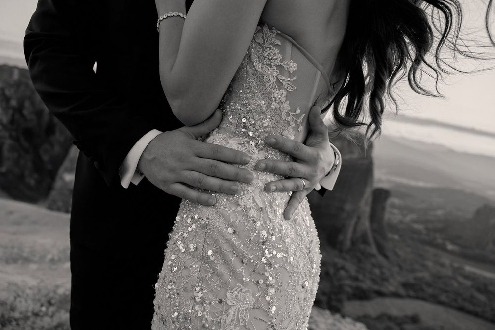 Black and white close-up shot of the groom embracing his bride around her waist.