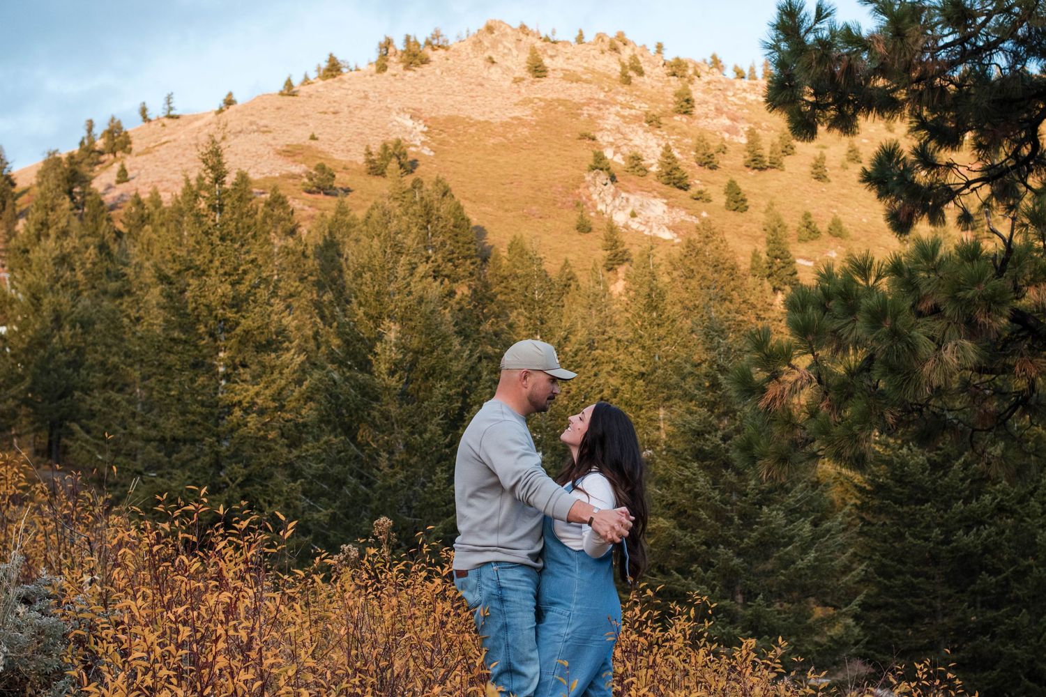 Couple holding hands in a lush green meadow with rolling hills in the background during an outdoor wedding shoot.