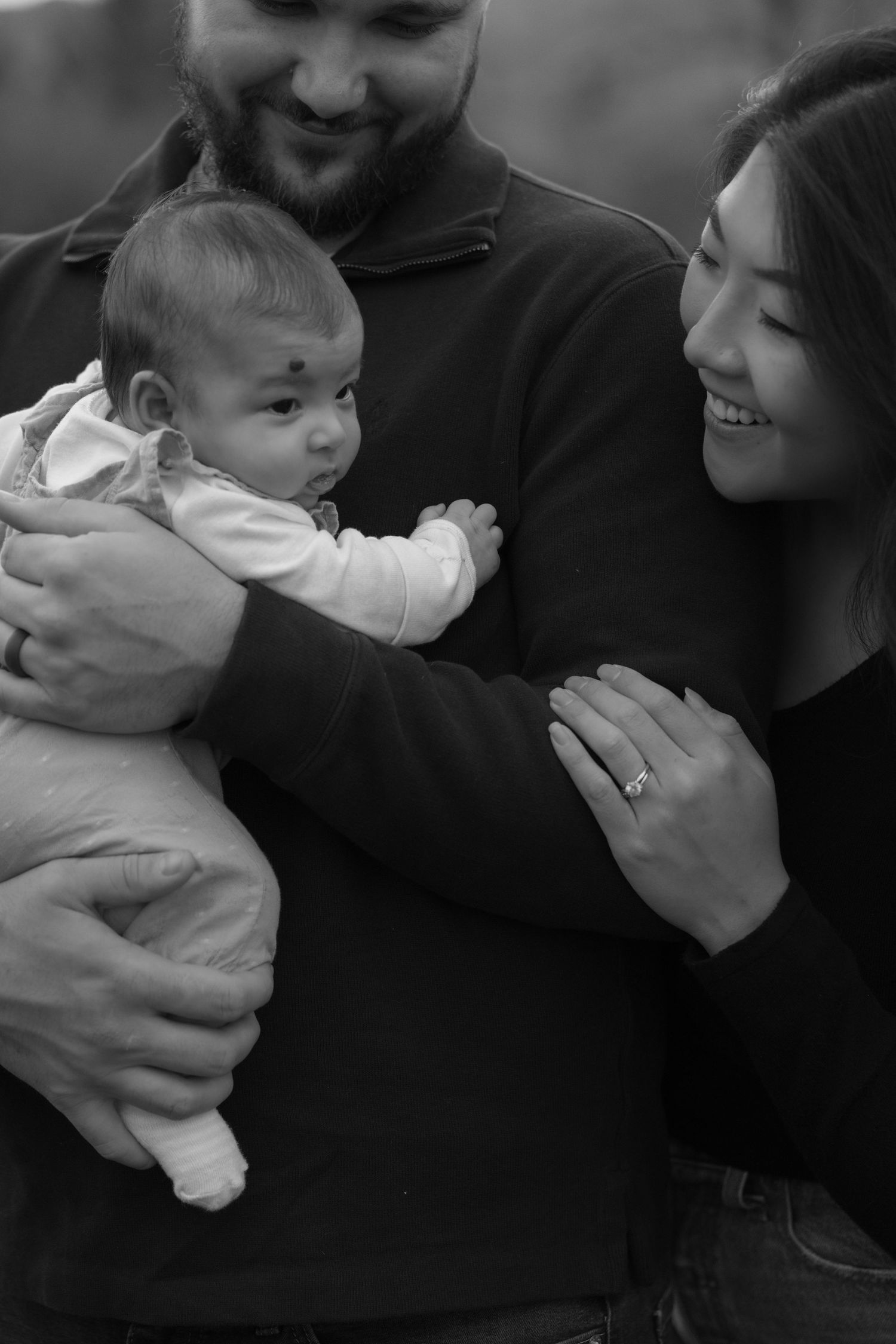 a close up portrait of mom and dad holding their infant and smiling lovingly during fall family mini session in hudson wisconsin