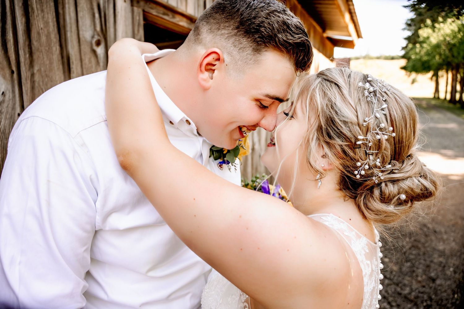 Bride and groom sharing a romantic forehead touch moment outdoors, bride wearing floral hair accessory.