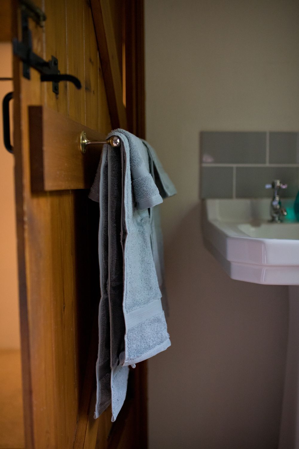 Gray towel hanging on wooden door with bathroom sink visible in background.