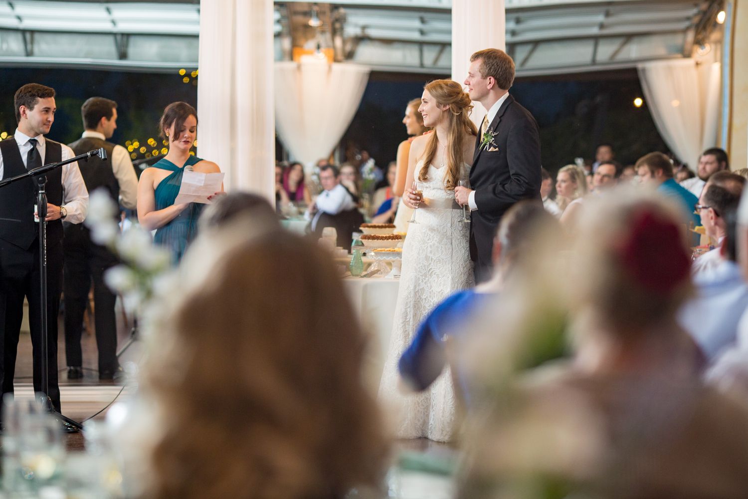 Wedding reception scene with blurred guests and elegant decor visible through white columns.