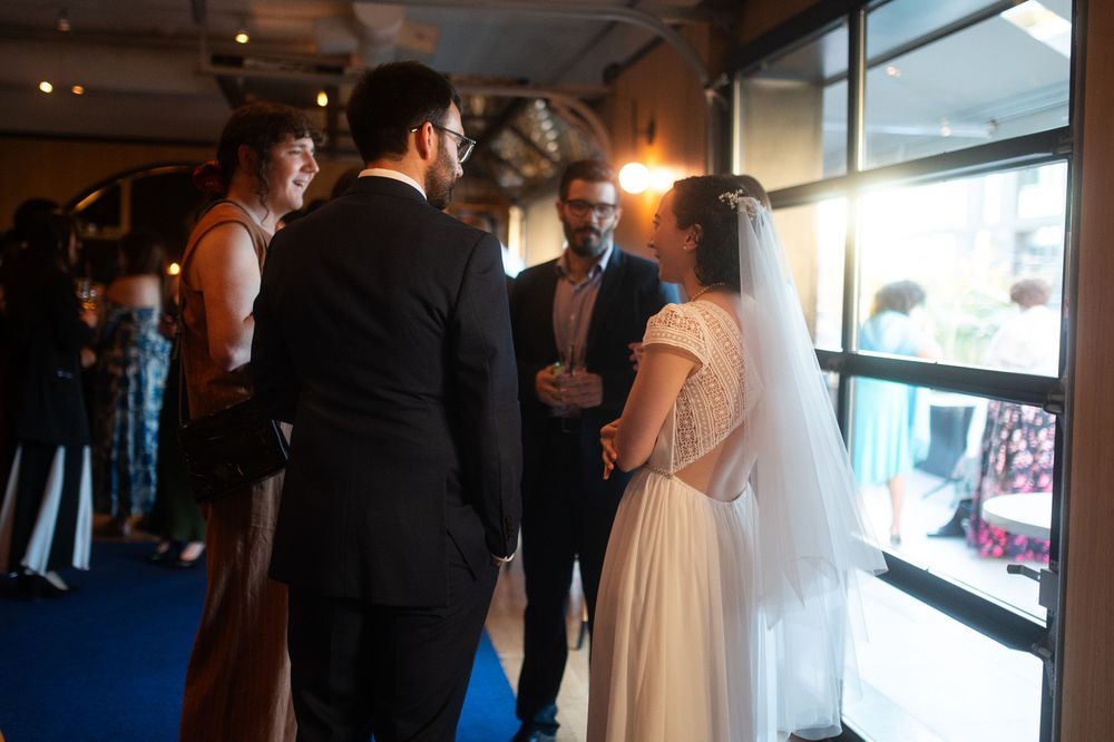 Bride and groom exchanging vows with officiant and witness at indoor wedding ceremony venue.