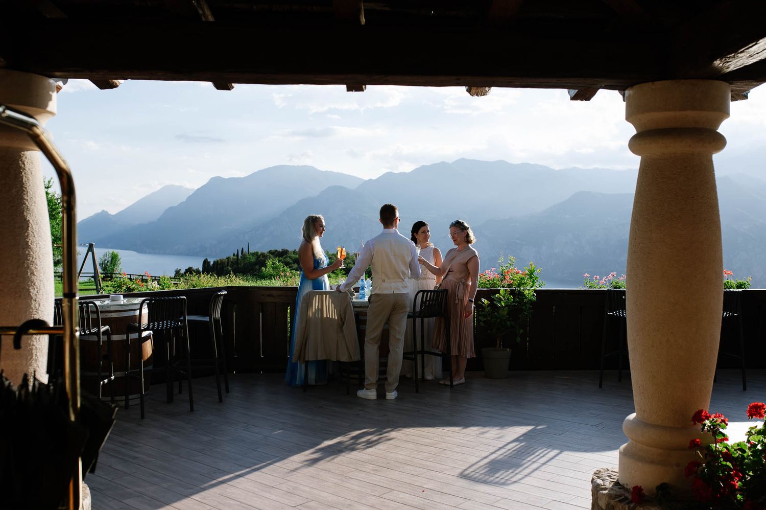 Wedding guests gather on a scenic mountain terrace overlooking a stunning lake and alpine landscape.