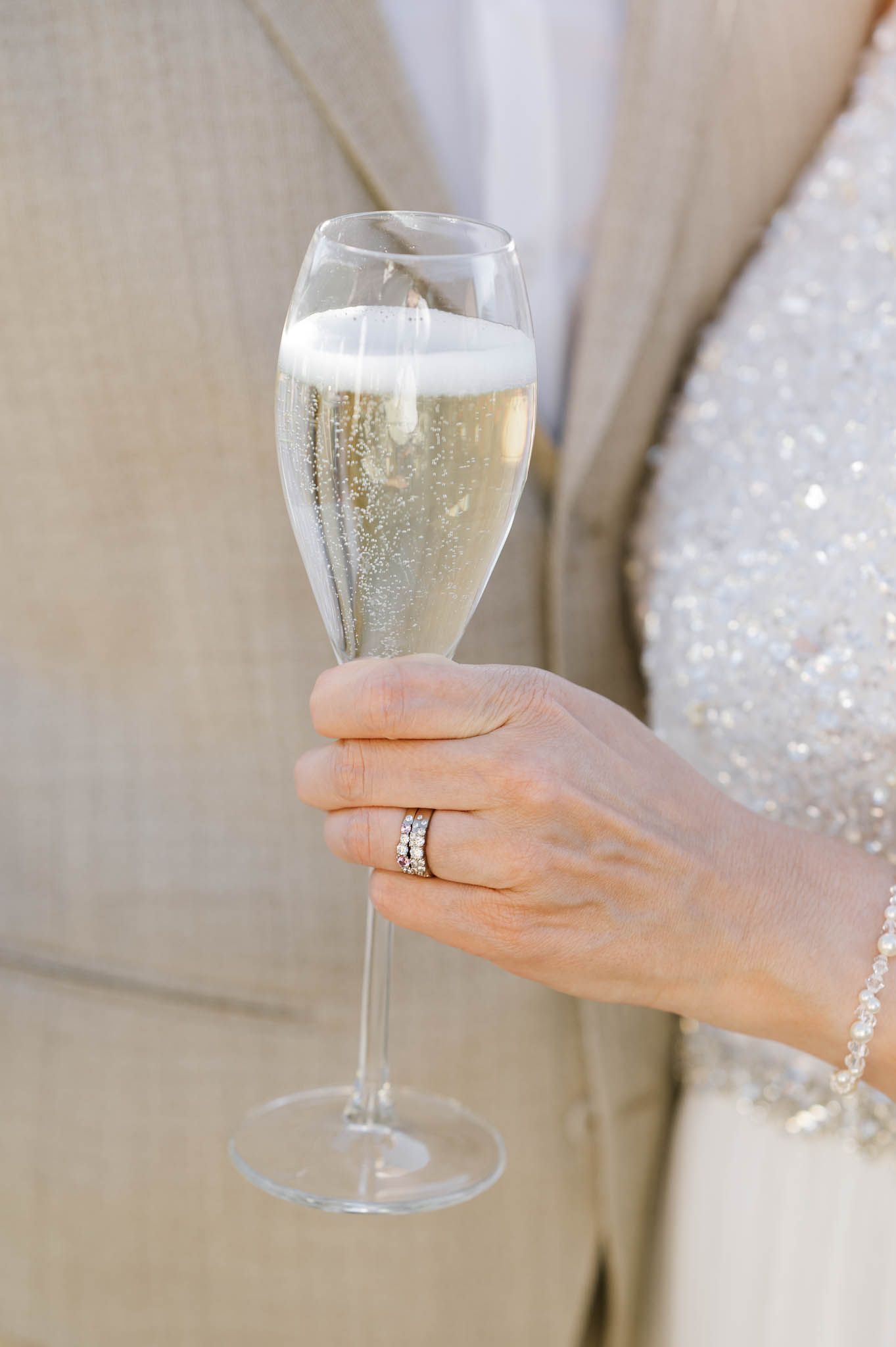 Bride holding champagne flute with diamond wedding ring visible after Italian lake wedding.