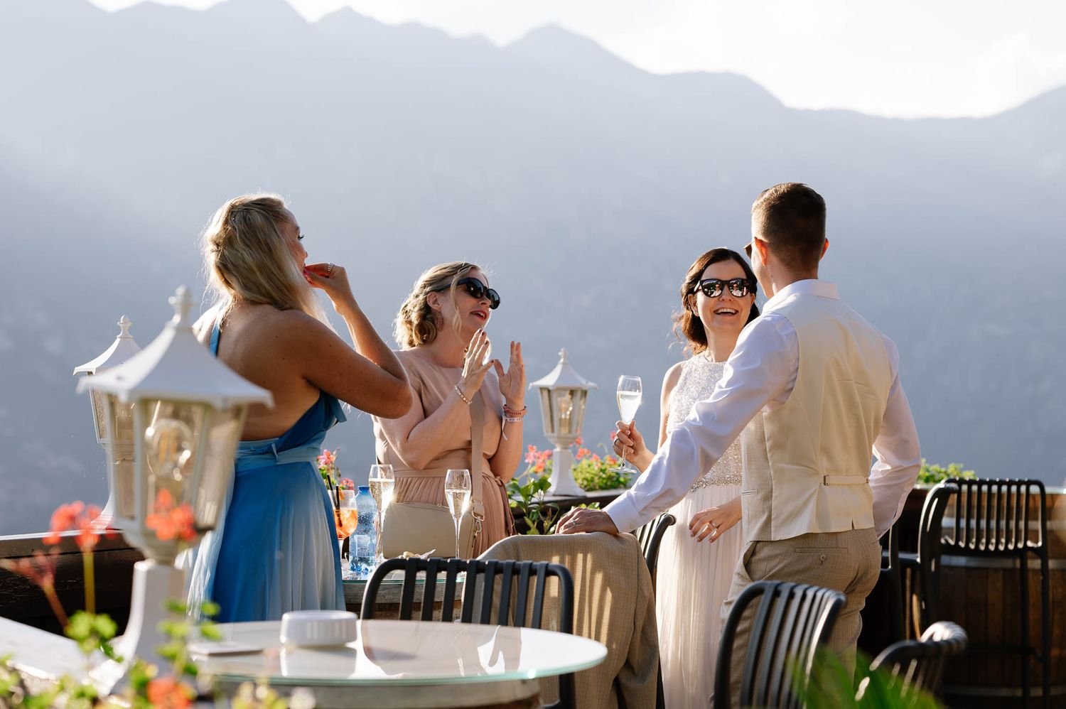 Wedding guests celebrate with champagne on a scenic mountain terrace with breathtaking valley views.