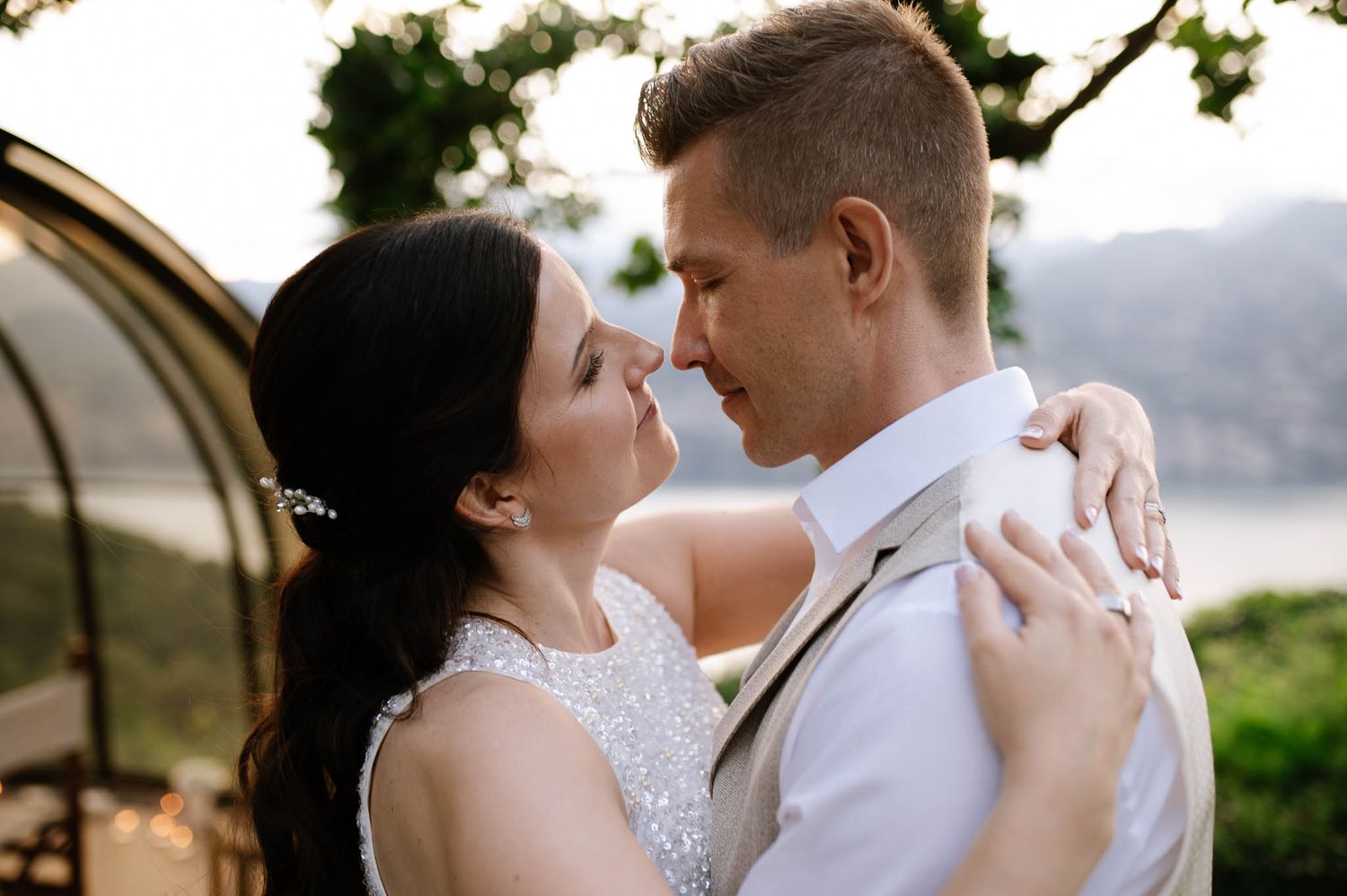Romantic couple embracing at outdoor wedding ceremony with scenic mountain view backdrop.