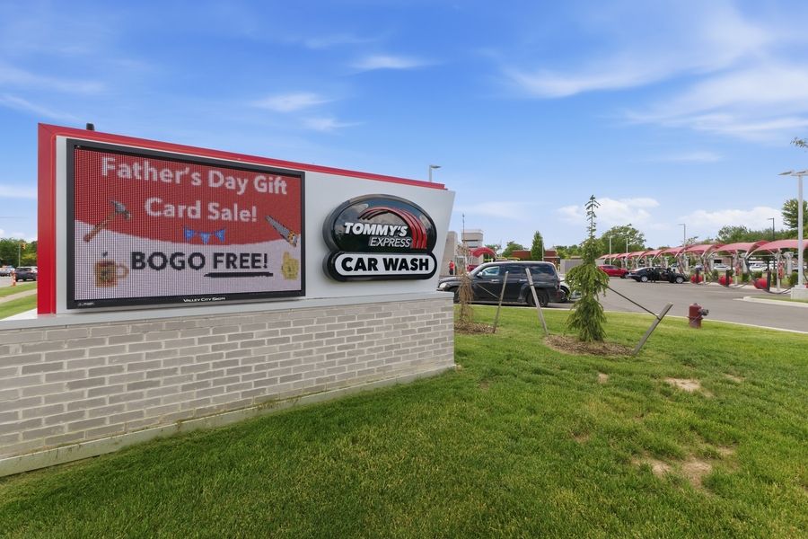 Tommy's Express Car Wash sign advertising a Father's Day Gift Card BOGO Free sale in a suburban parking lot.