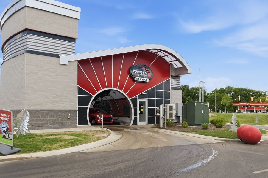 Tommy's Express Car Wash entrance featuring a bold red sunburst design above the drive-through tunnel.
