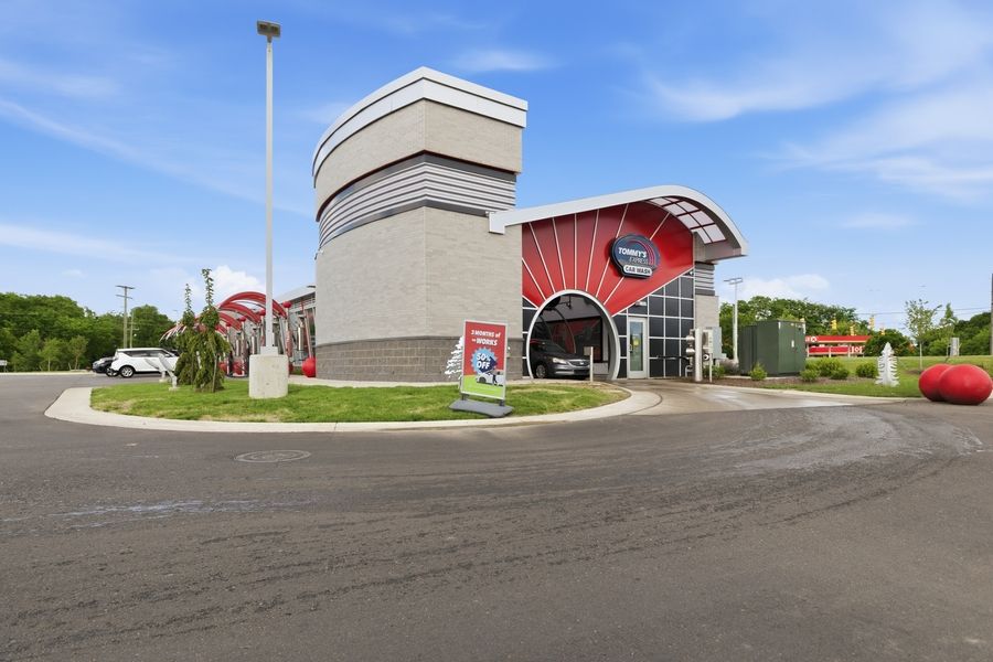 Exterior view of a modern fast food restaurant with red accents and curved architecture surrounded by a parking lot.