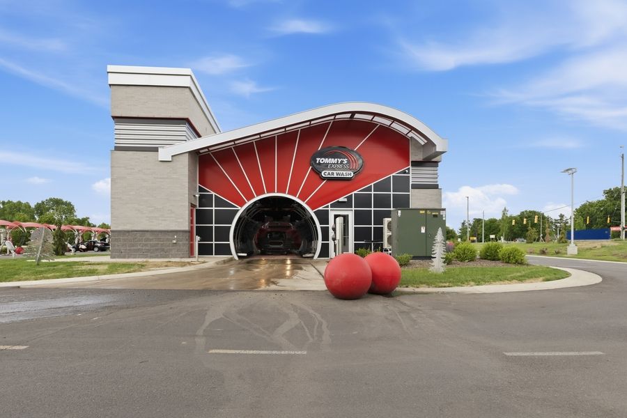 Tommy's Express Car Wash entrance featuring bold red sunburst design, large decorative red spheres, and curved architectural details.