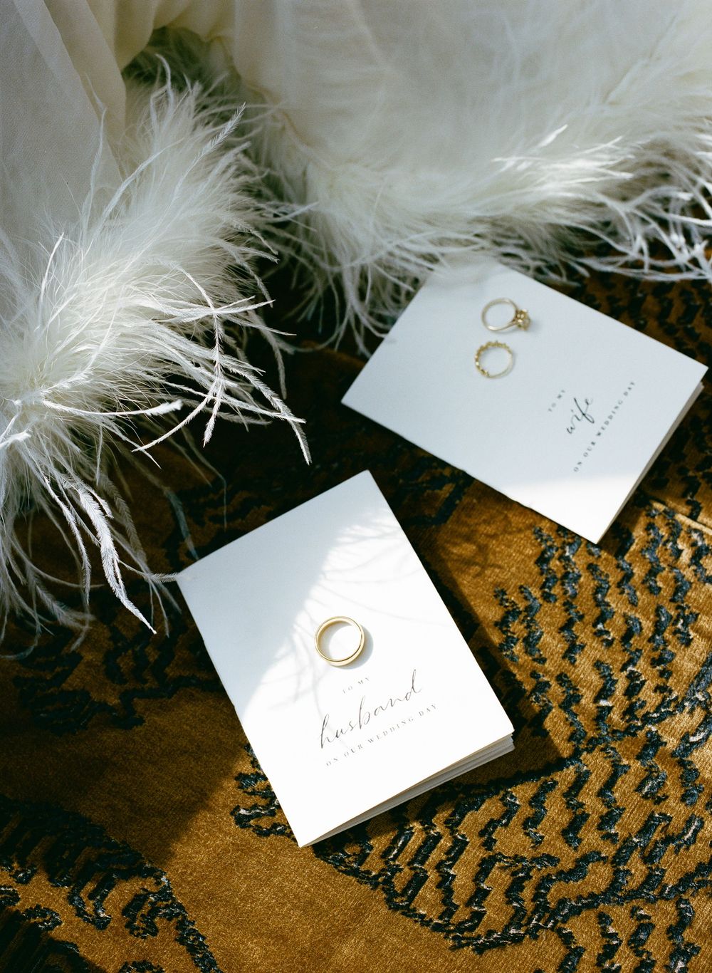 Wedding rings displayed on white jewelry boxes with feather dress, hotel particulier wedding, paris wedding film photography, paris bride