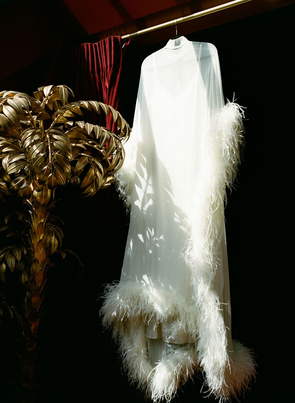White feather-trimmed gown hanging red velvet paris, paris hotel particulier montmartre wedding photography, film wedding photographer