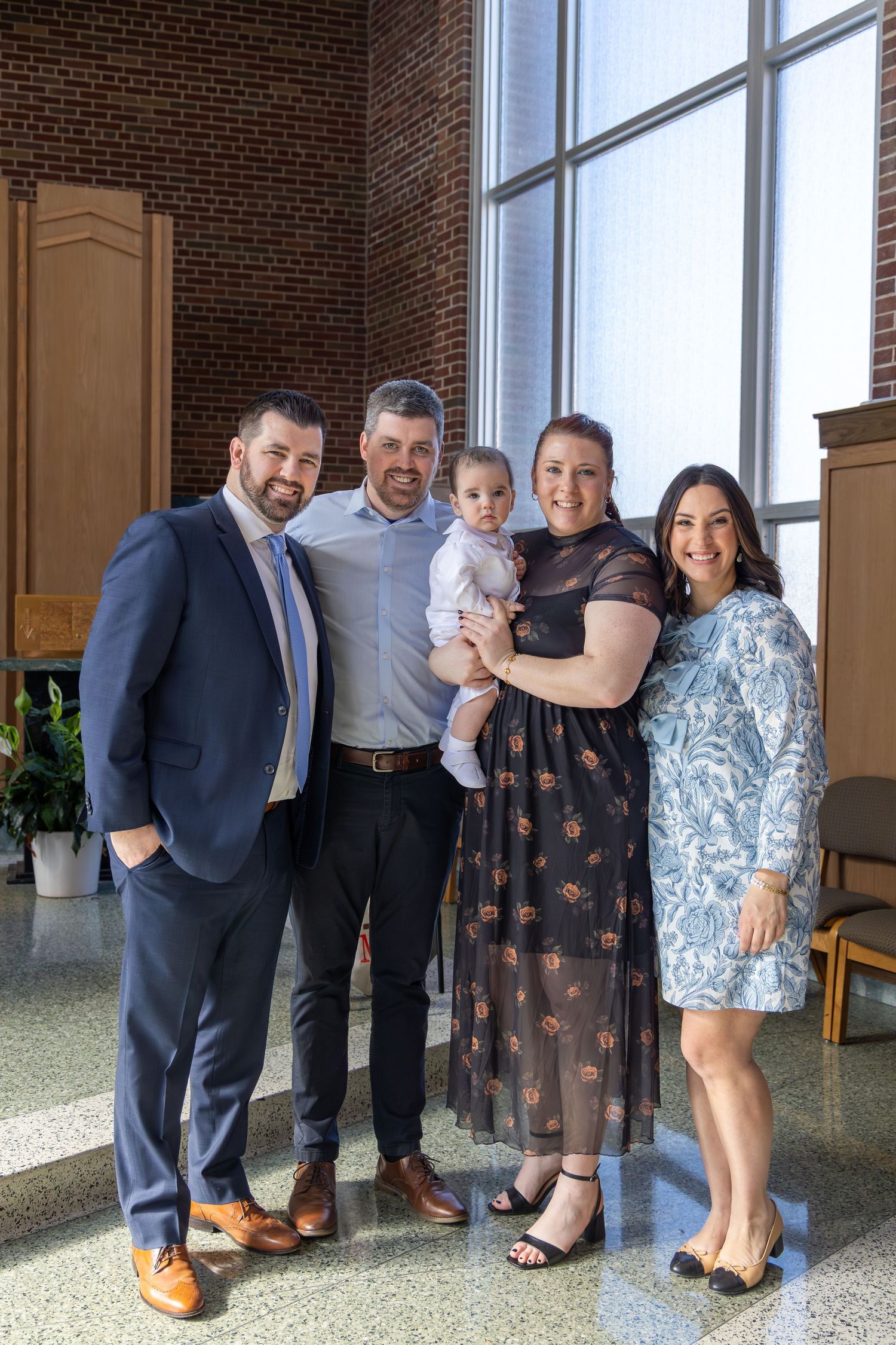 A series of five casual group photos taken in front of large windows and brick walls.