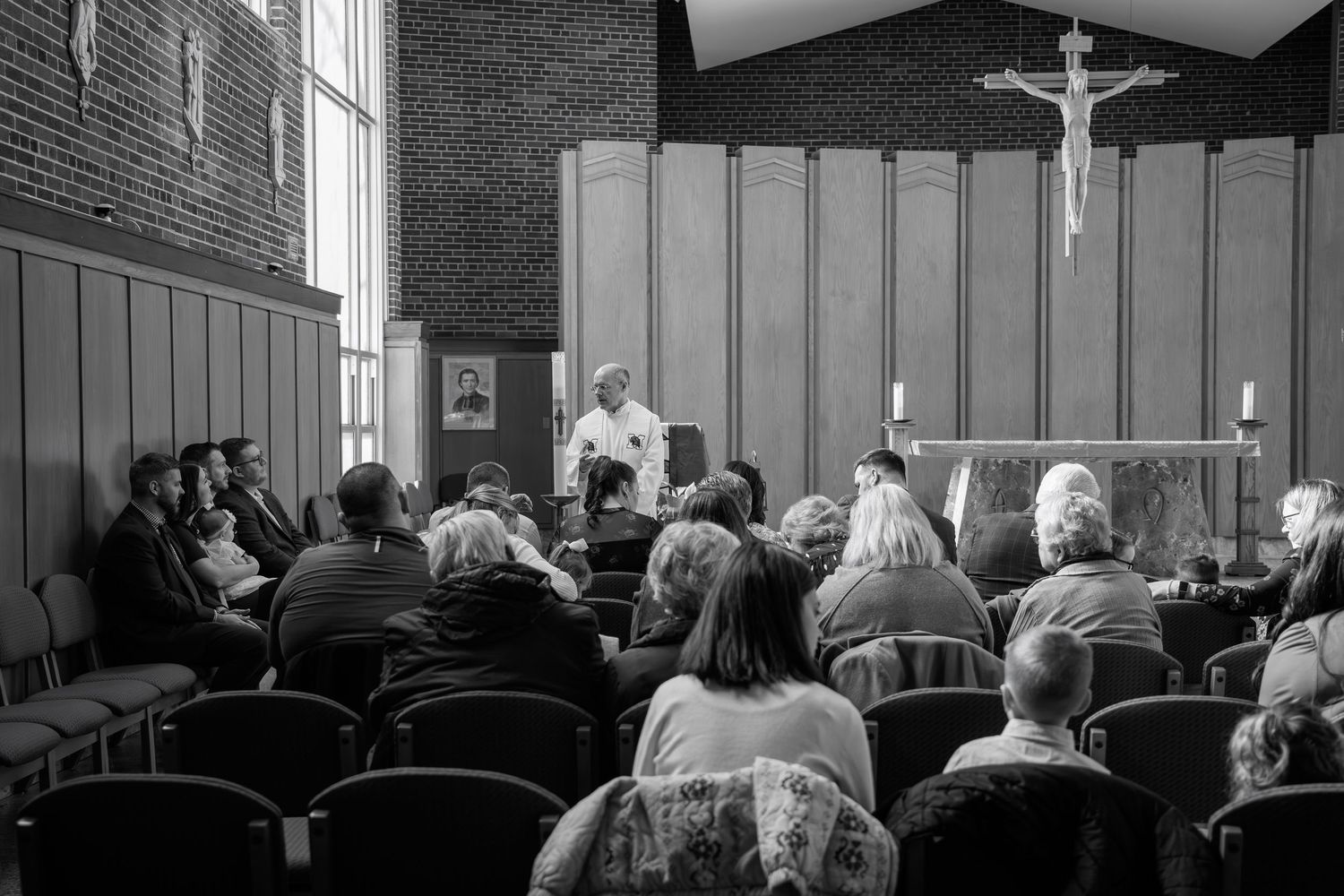A black and white photograph shows people sitting in church pews during a religious service.
