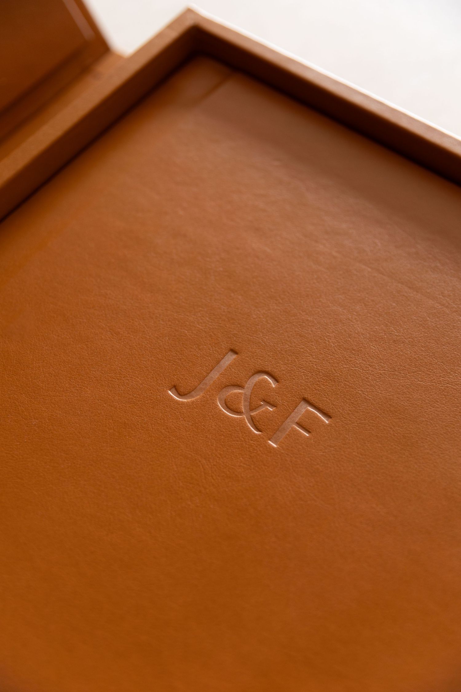 Close-up of tan leather tray with embossed J&F monogram initials, elegant personalized accessory.