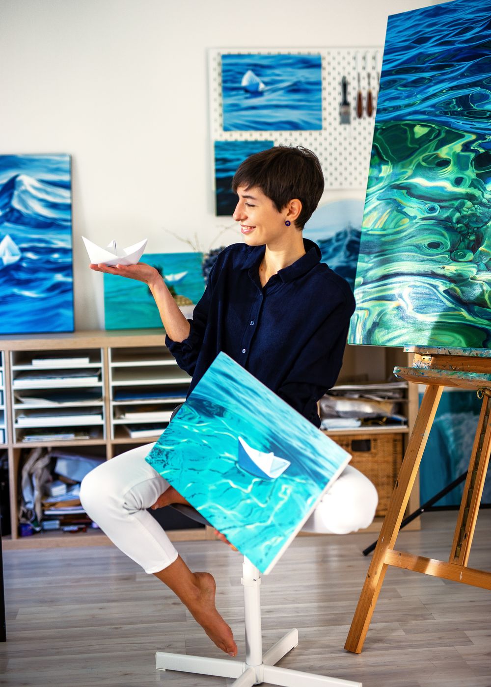 A person in a navy shirt performs a playful dance sequence in front of blue and turquoise ocean-themed artwork.
