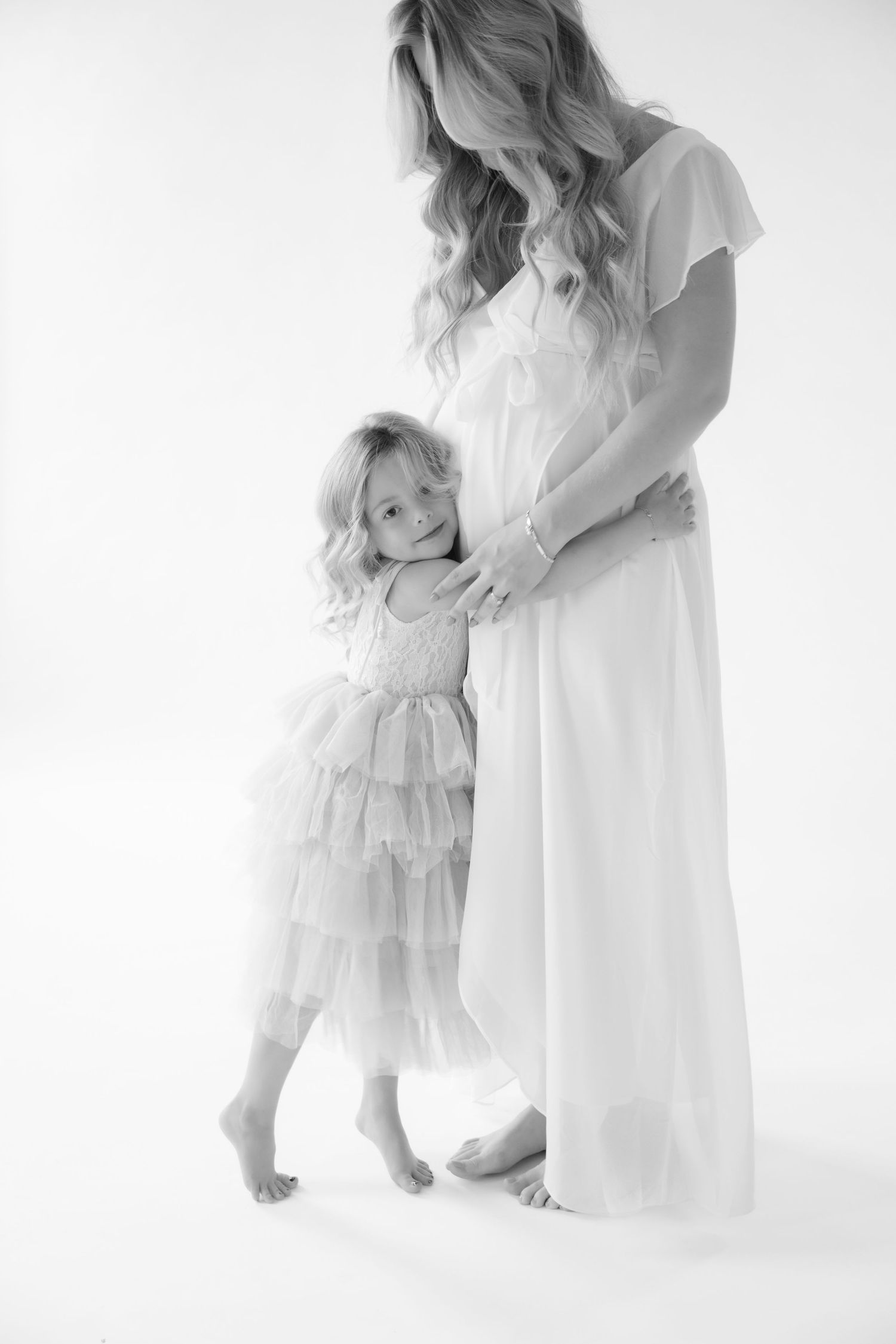 daughter hugs moms baby bump during in studio maternity session in stillwater mn. Portraits with Jagger Rose Photography