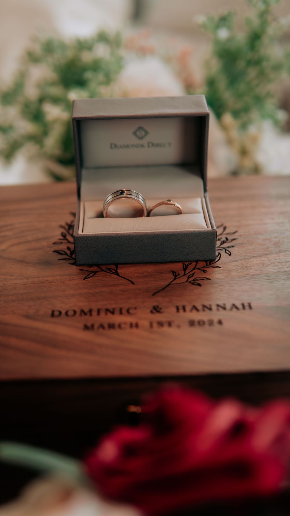 Two wedding bands in a Diamonds Direct box on an engraved wooden box reading Dominic & Hannah March 1st 2024.