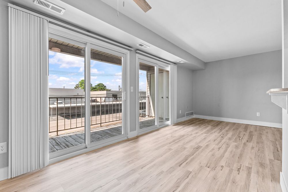 Spacious empty room with large sliding glass doors opening to an outdoor balcony and light hardwood floors.