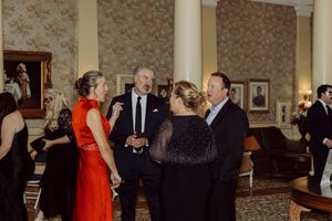 Guests in formal attire engage in conversation at an elegant masquerade ball reception.