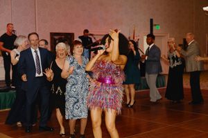 Live performer in sparkly dress entertaining dancing guests at elegant ballroom reception.
