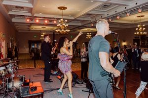Energetic band performance with singer dancing on stage at upscale ballroom event.