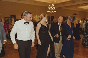 Guests dancing in formal attire at elegant ballroom reception under chandelier lighting.