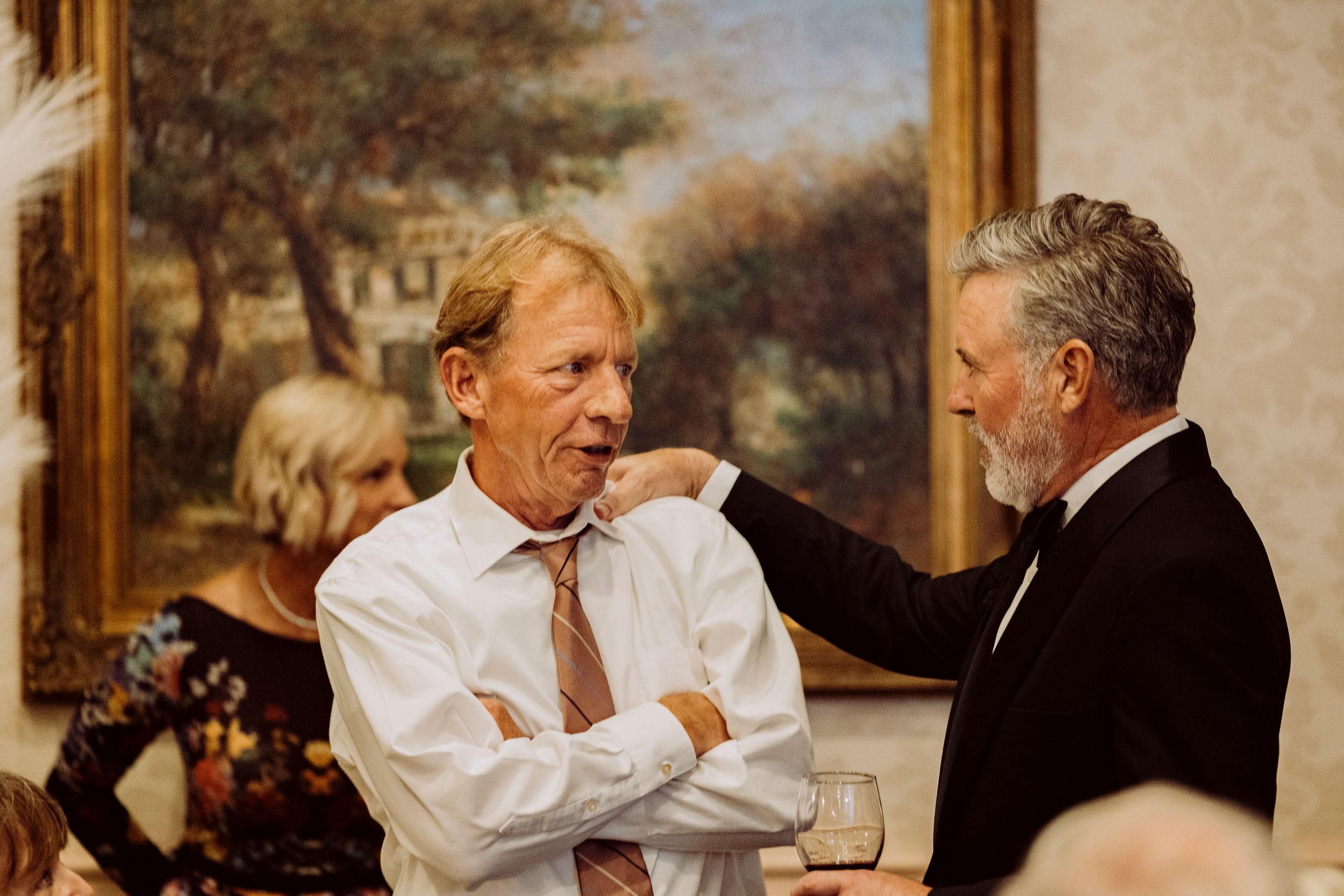 Two men in formal attire share a friendly conversation at an upscale evening event.