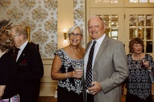 Smiling couple poses together holding drinks at a formal black-tie gala event.