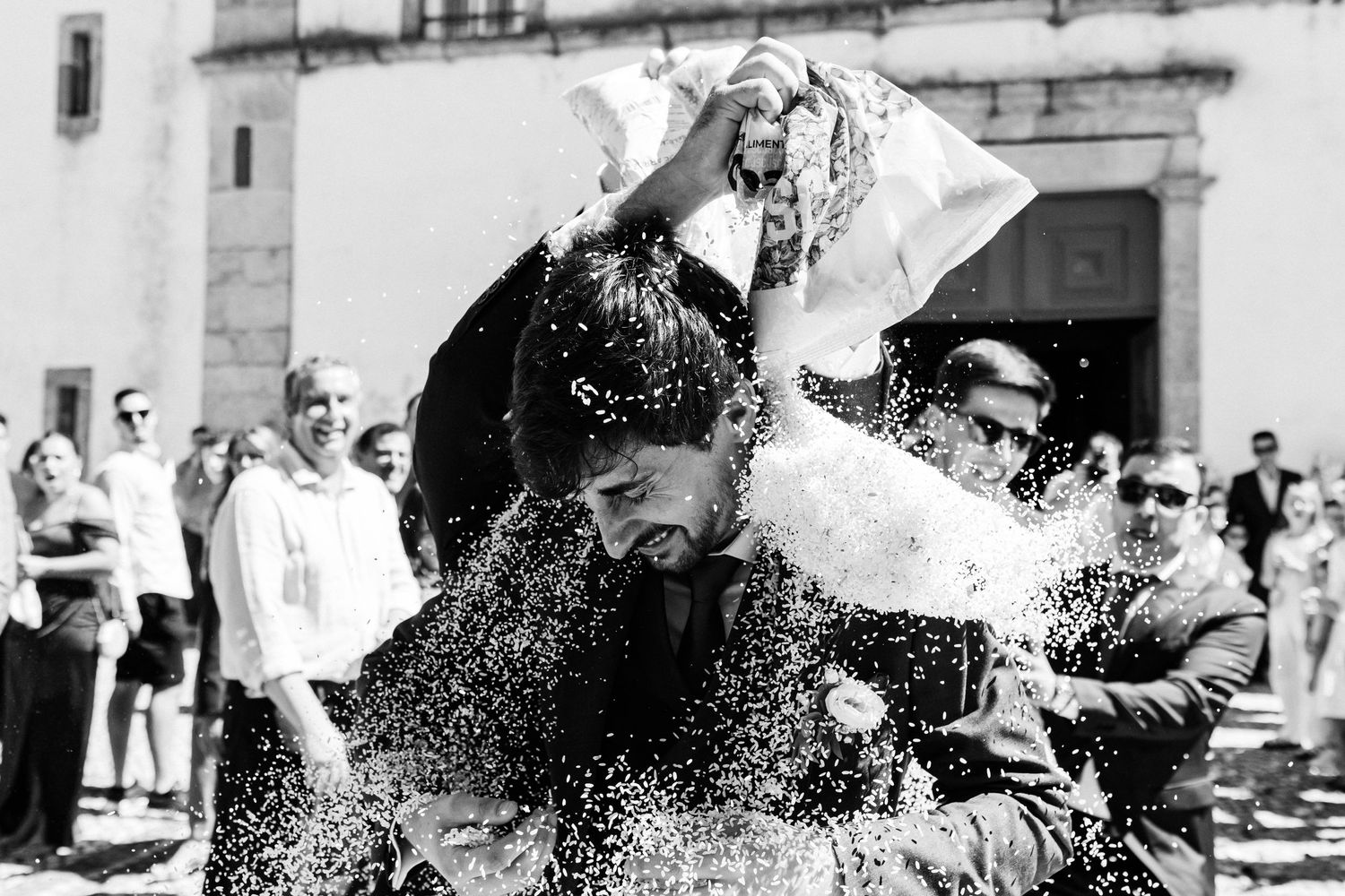A black and white photo shows rice being thrown to the couple