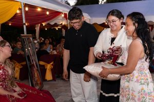 Guests exchanging gifts at an elegant outdoor evening celebration under a decorated tent with warm string lights.